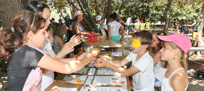 Un enfant avec les yeux bandés essaye de reconnaître des fruits et des légumes données par d'autres enfants