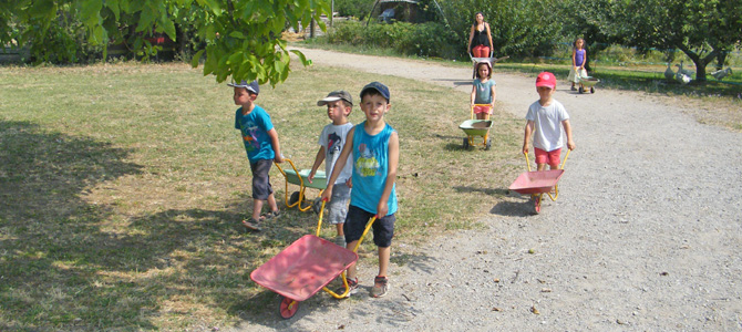 Des enfants et un animateur poussent des brouettes