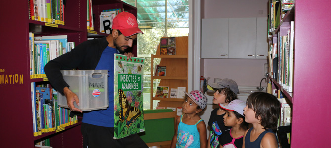 Un animateur présente un livre à un groupe d'enfants dans la médiathèque de l'Écolothèque