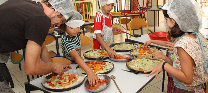 Un groupe d'enfant acompagné d'un animateur préparent des tartes de légumes