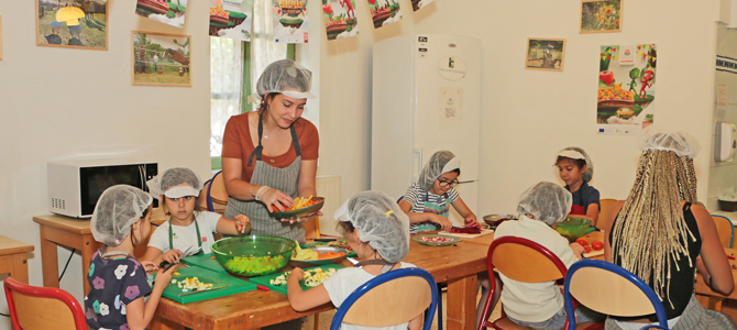 Un groupe d'enfant acompagné de deux animatrices préparent des verrines de légumes du potager de l'Écolothèque