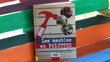 Livre "Les meubles en palettes" contre une palette peinte multicolore