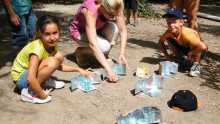 Des enfants accompagnés d'une animatrice utilisent des chauffe-verres solaire pour chauffer de l'eau