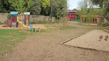 Vue sur un espace arboré avec des jeux pour enfants et une pergola