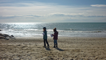 Deux enfants sont sur la plage avec des papiers à la main