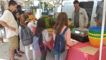 un groupe d'enfants avec leur animateur sont devant le stand d'un maraîcher au marché de Celleneuve