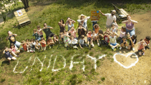 Un groupe d'enfants derrière le mot Uniday écrit avec de la farine dans l'herbe