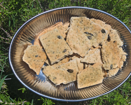 Des crackers dans un plat sont disposés sur du romarin