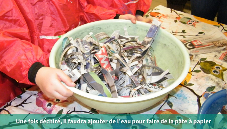 un enfant tient une bassine avec les lamelles de papier journal