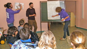 Trois agents expliquent à un groupe d'enfants comment un arbre se nourrit expliquant le rôle des racines