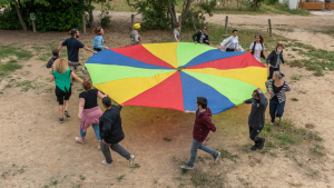 un groupe d'adultes fait tourner une toile colorée de parachute