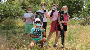 5 enfants posent avec leurs accessoires de tournage : prompteur, clap, trépied, fiches...