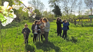 Un groupe d'enfants avec des parents et un animateur observent à la jumelle et identifient à l'aide d'un livre des oiseaux sauvages à l'Écolothèque