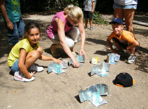 Des enfants accompagnés d'une animatrice utilisent des chauffe-verres solaire pour chauffer de l'eau