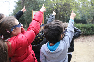 Des enfants équipés de lunettes d'observation pour éclipse solaire pointent un doigt en direction du Soleil