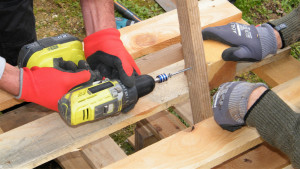 Des mains en gros plan vissent des morceaux de bois