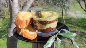 Une verrine de tapenade avec des couches noires et vertes avec deux tranches de pain grillées