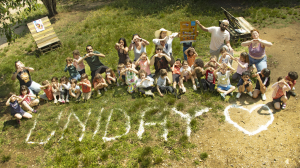 Un groupe d'enfants derrière le mot Uniday écrit avec de la farine dans l'herbe