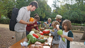 un groupe d'enfants et deux animateurs préparent des lanternes avec des courges